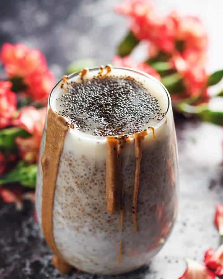 chia seeds pudding in a glass with flowers around