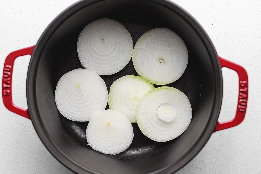 slices of onion in the bottom of a dutch oven