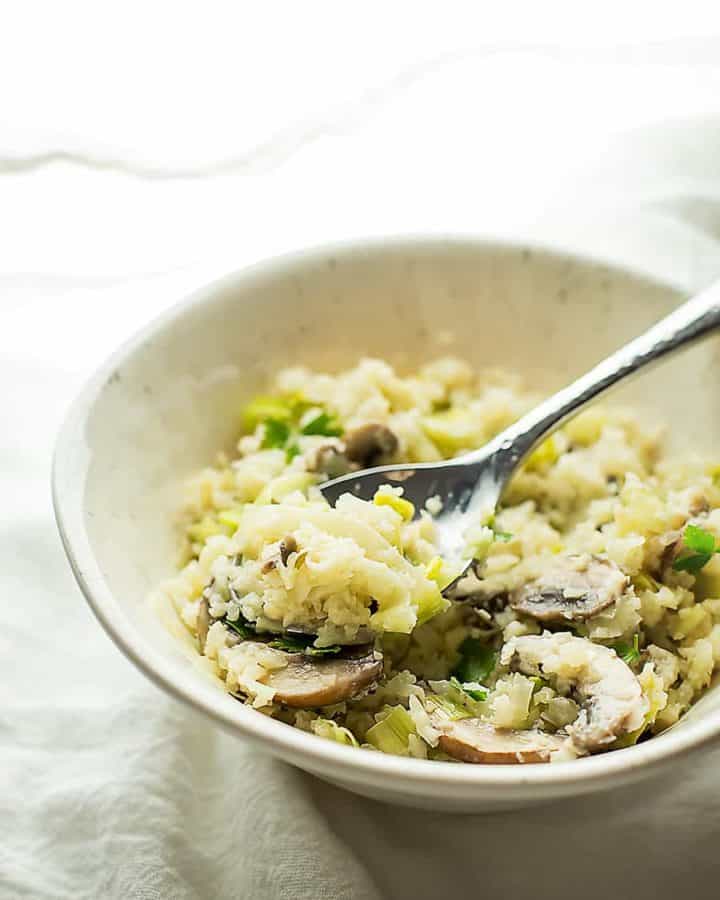 cauliflower risotto in a white bowl with a spoon