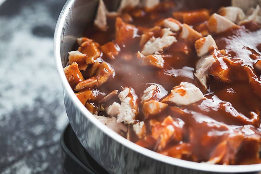 chicken and enchilada sauce simmering in a skillet