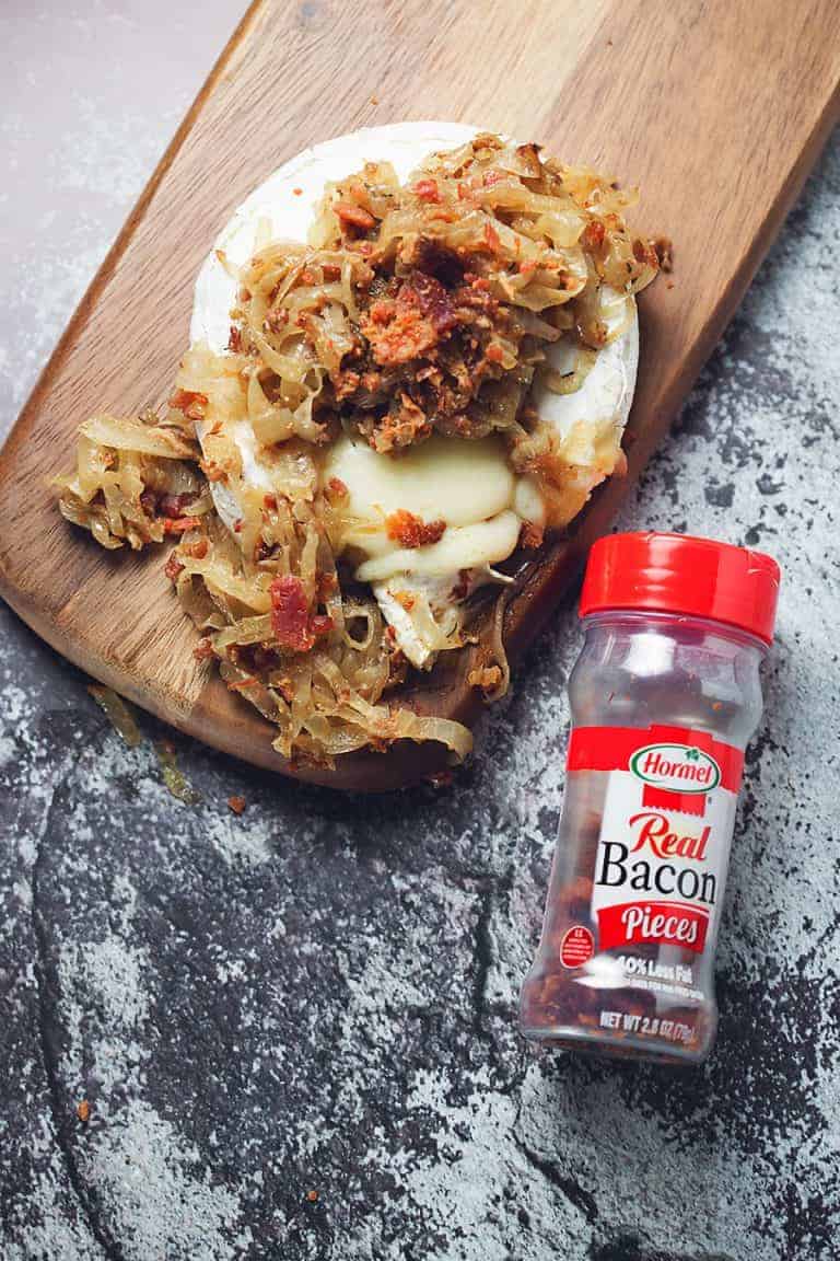 baked brie with caramelized onions and bacon on a wooden serving tray