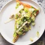 a slice of ceasar salad pizza on a white plate