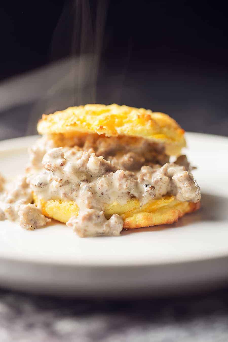 a low carb cheddar biscuit with sausage gray on a white plate