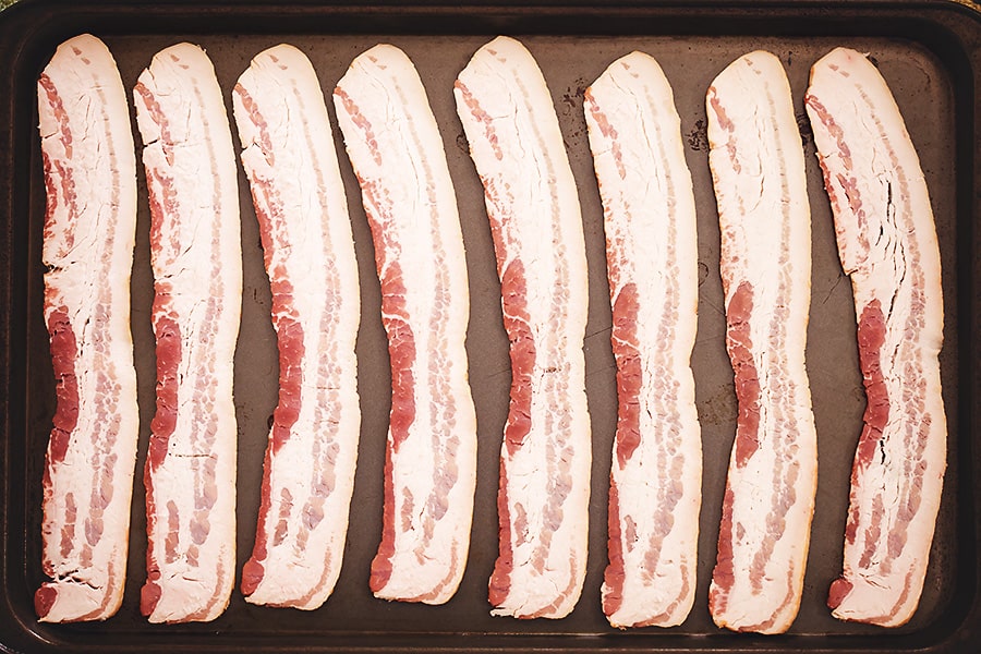 8 pieces of raw bacon on a sheet pan 