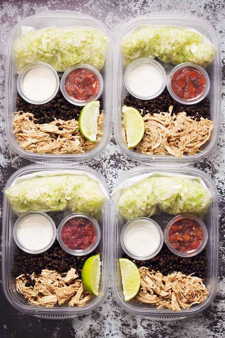 meal prep containers with lettuce, black lentils, chicken breast, sour cream, and salsa