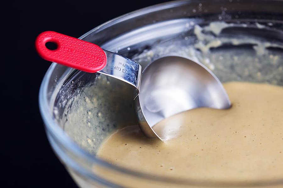 pancake batter in a glass bowl with a measuring spoon