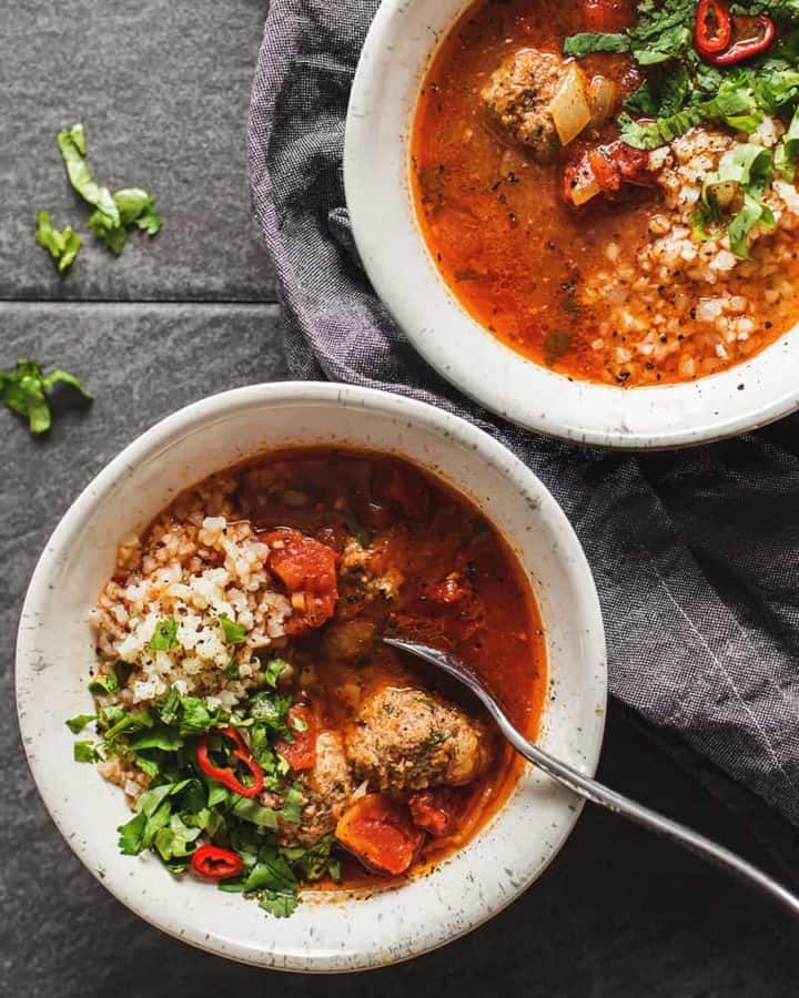 Albondigas mexican meatball soup in a white bowl on a gray background