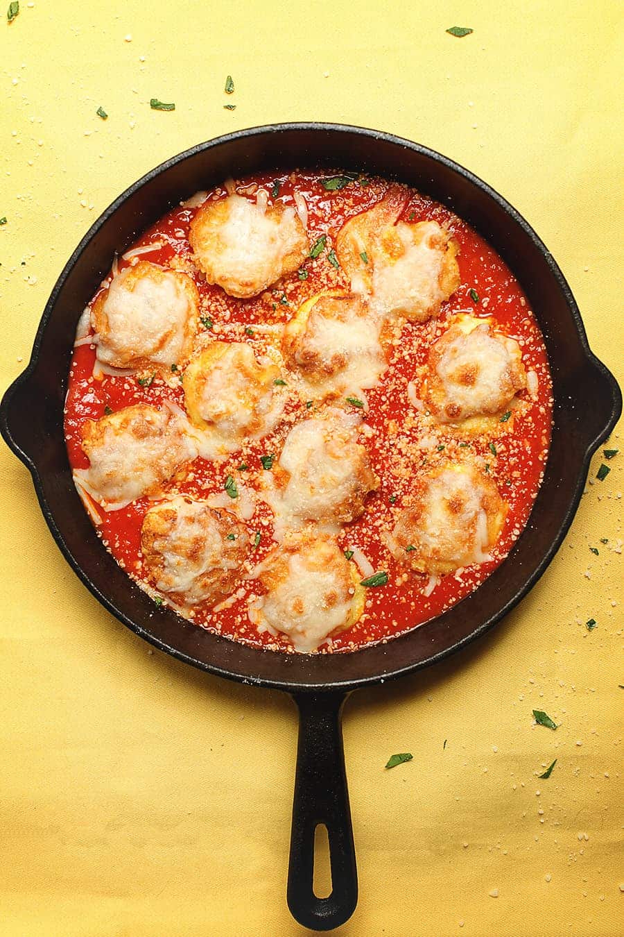 shrimp parmesan in a cast iron skillet on a yellow table cloth