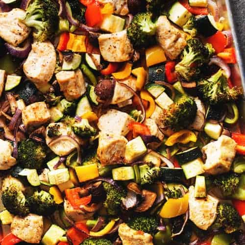 a sheet pan full of chicken and vegetables. Broccoli, bell pepper, onion, zucchini, and mushrooms