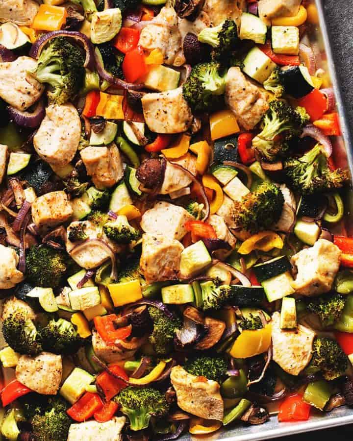 a sheet pan full of chicken and vegetables. Broccoli, bell pepper, onion, zucchini, and mushrooms