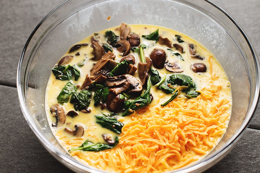 mushrooms, spinach, cheese, and beaten egg in a glass bowl