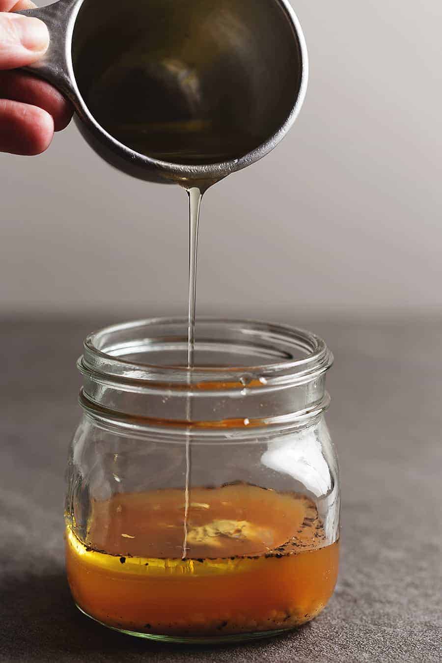 oil being poured into a jar to make dressing