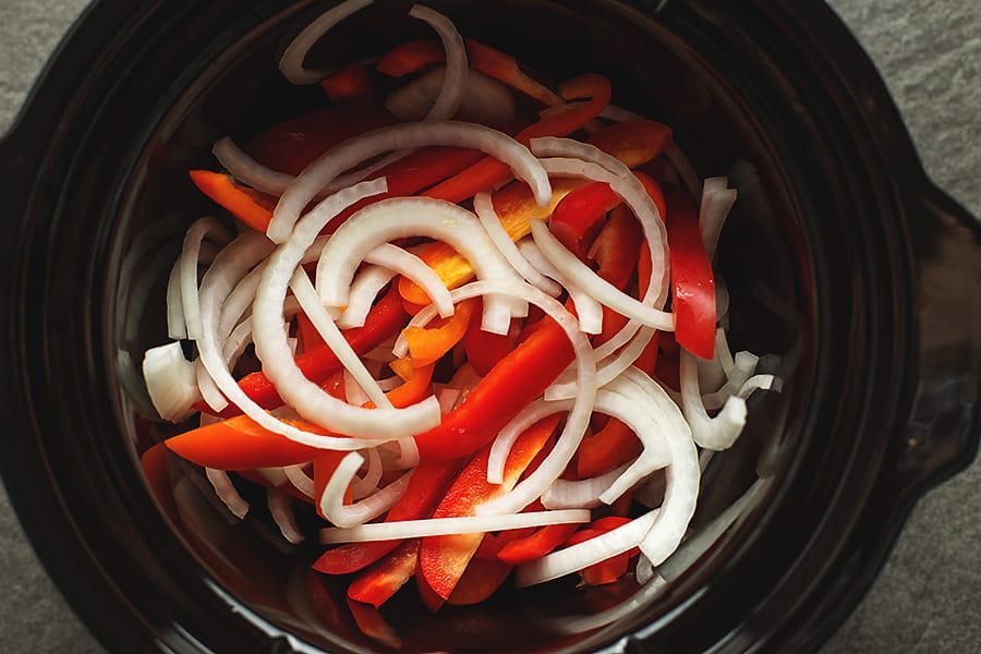 sliced onions and peppers in a crock pot