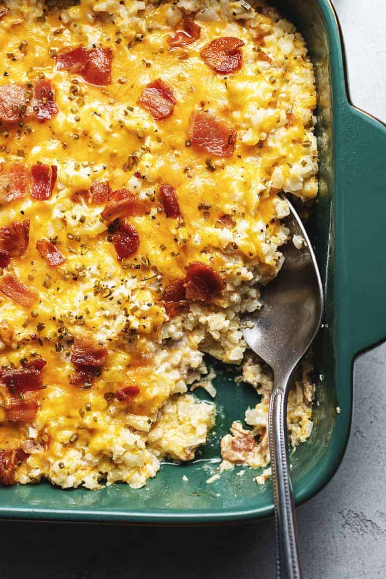 cheesy loaded cauliflower rice casserole in a green dish
