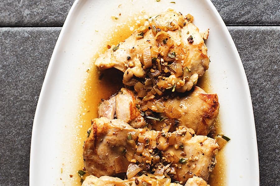 boneless skinless chicken thighs with sauce on a white platter
