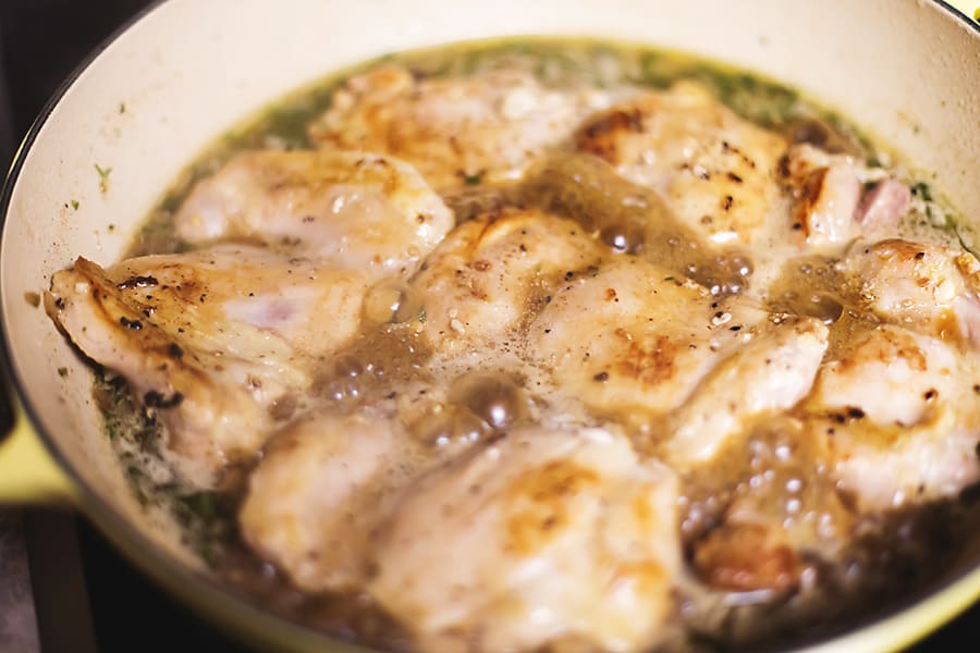chicken thighs simmering in sauce