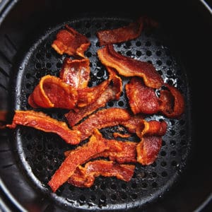 cooked bacon in an air fryer basket