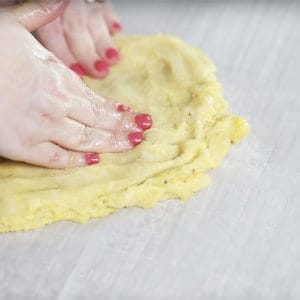 pizza crust being spread onto parchment paper