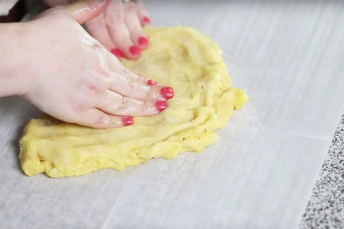 pizza dough being spread with hands