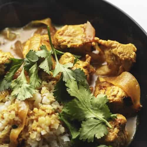 Indian curry chicken with cilantro in a black bowl