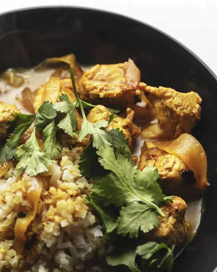 Indian curry chicken with cilantro in a black bowl