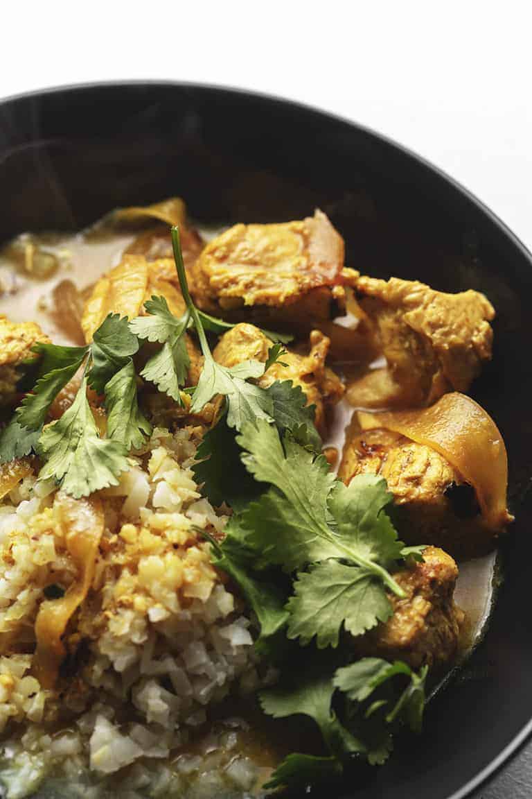 Indian curry chicken with cilantro in a black bowl