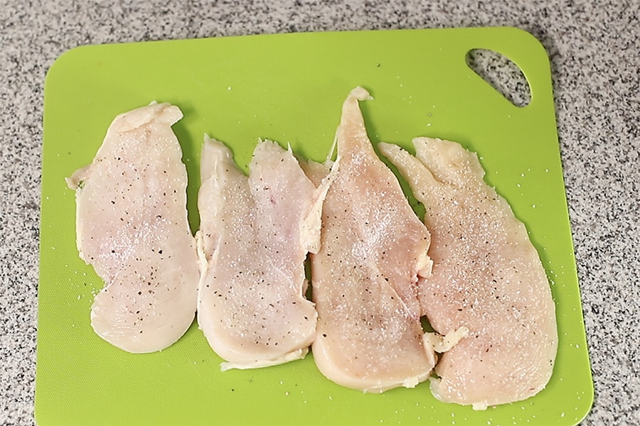 seasoned chicken cutlets on a cutting board.