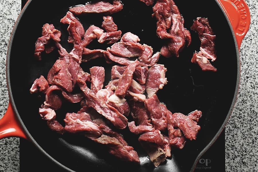 thin sliced beef in a red skillet