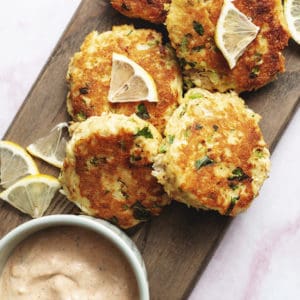keto crab cakes garnished with remoulade sauce on a wood platter