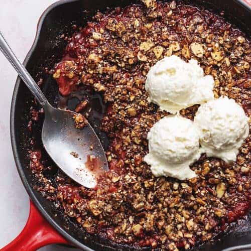keto strawberry crisp in a skillet with ice cream