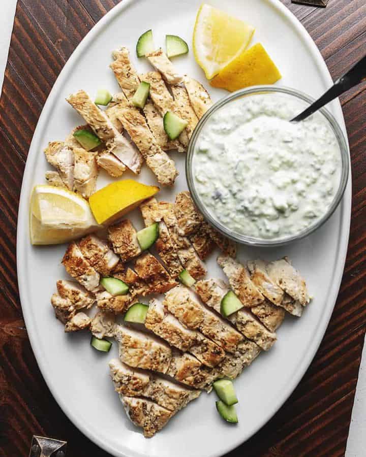 greek chicken with tzatziki on a white serving plate