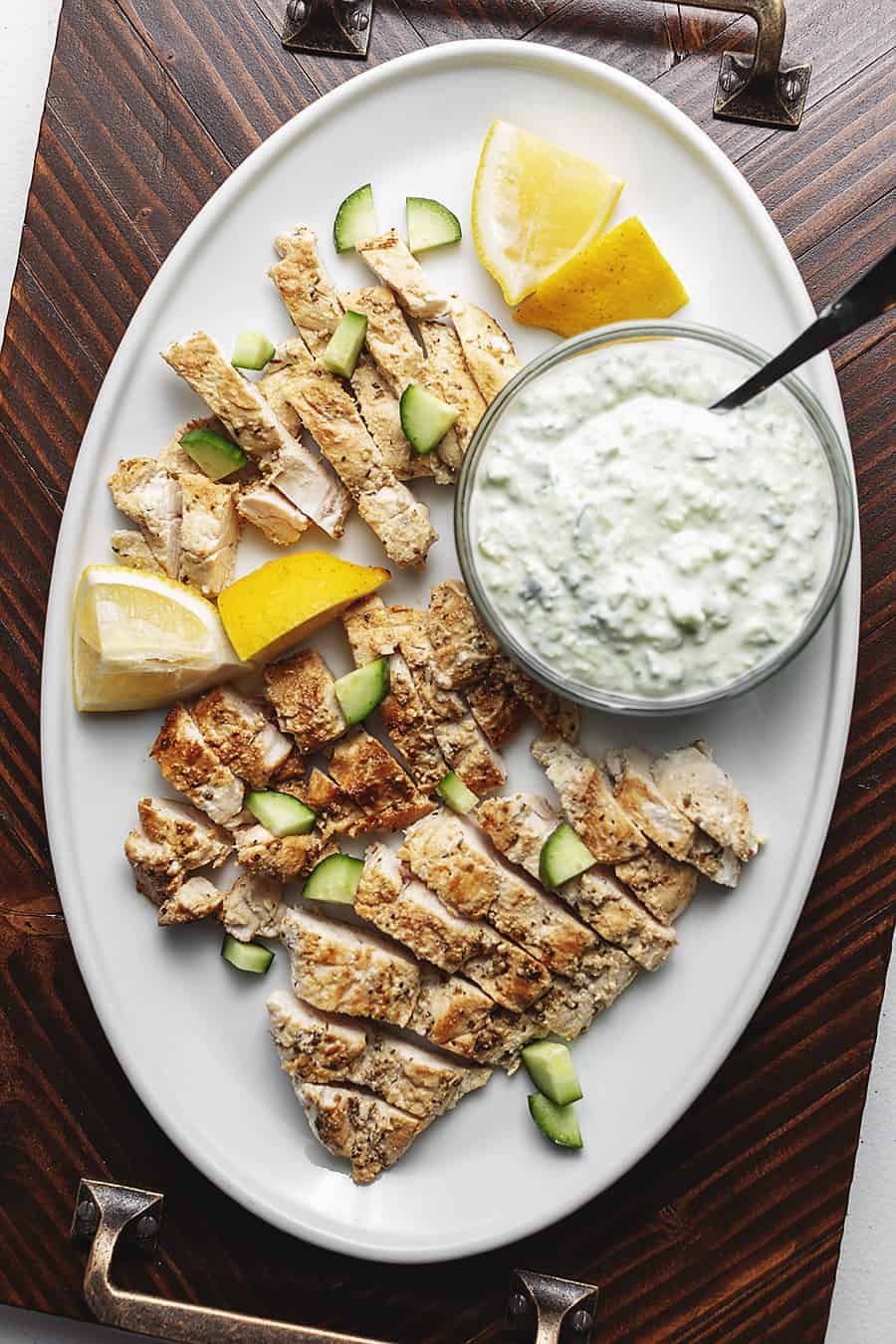 greek chicken with tzatziki on a white serving plate