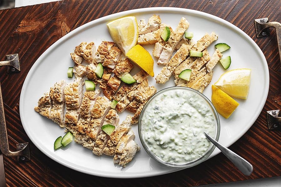greek chicken with easy tzatziki sauce on a while platter