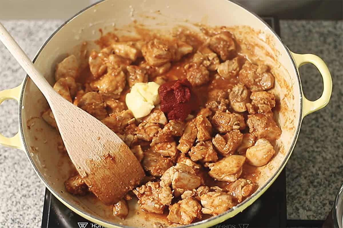 adding spices to a skillet for keto butter chicken