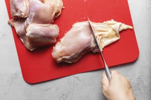 chicken thighs on a red cutting board