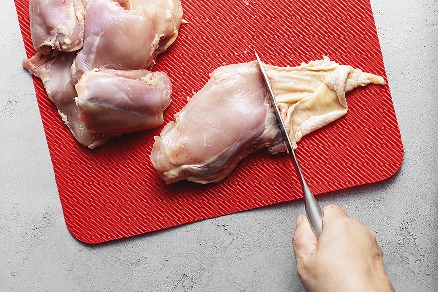 chicken thighs on a red cutting board 