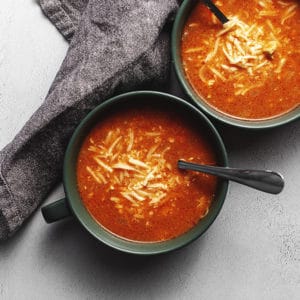 chicken enchilada soup in serving bowls with cheese