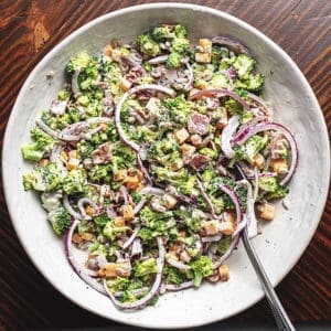 bacon cheddar broccoli salad in a white glass bowl