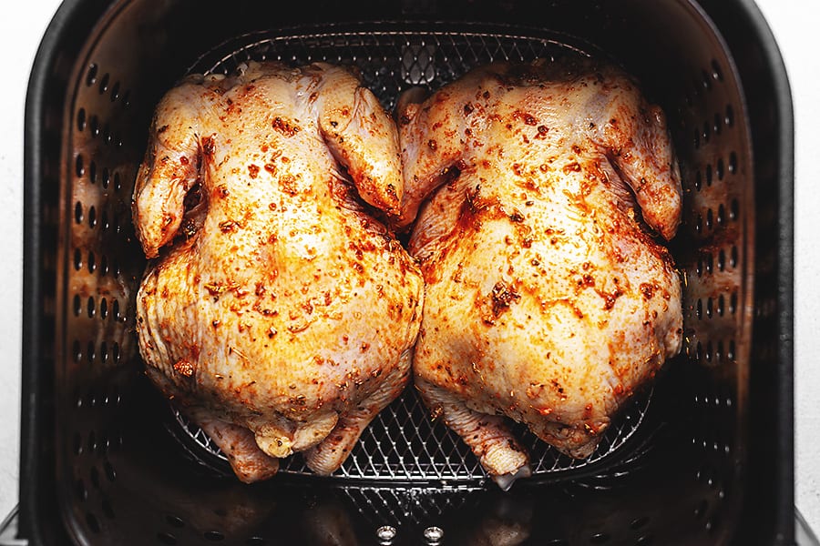 Cornish hens with seasoning side by side in air fryer 