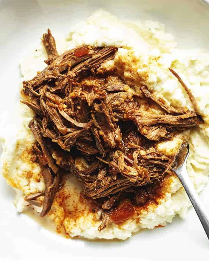 saucy London broil with cauliflower mash in a white plate