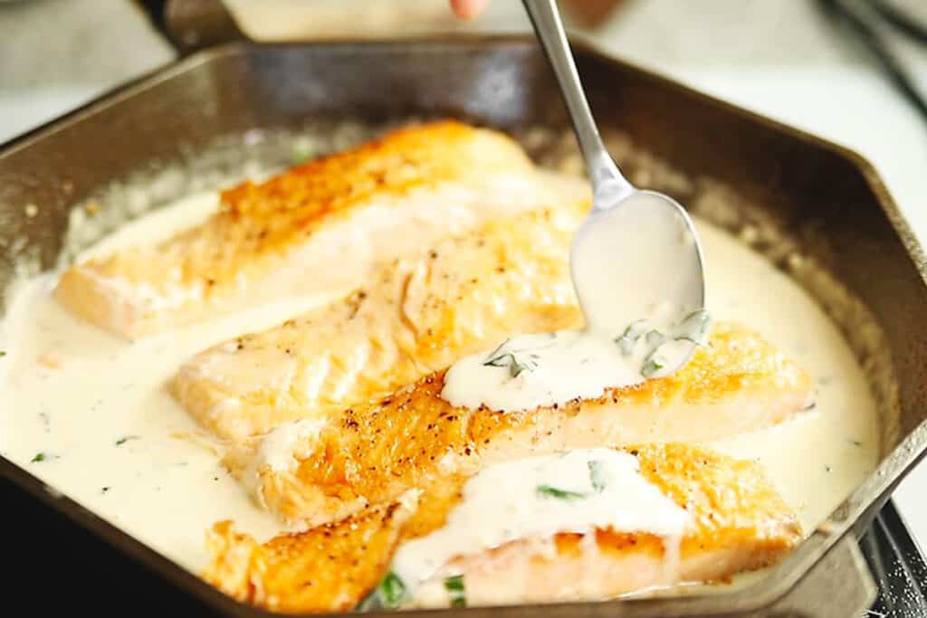 Keto salmon topped with creamy garlic sauce and fresh parsley