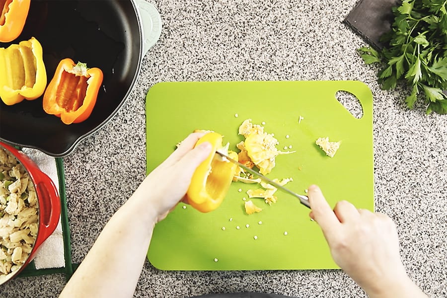 cleaning out peppers on a green cutting board