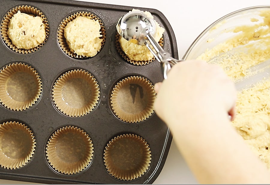batter being scooped into a muffin tin