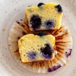 Keto blueberry muffin cut in half to show the soft, fluffy inside with blueberries throughout.
