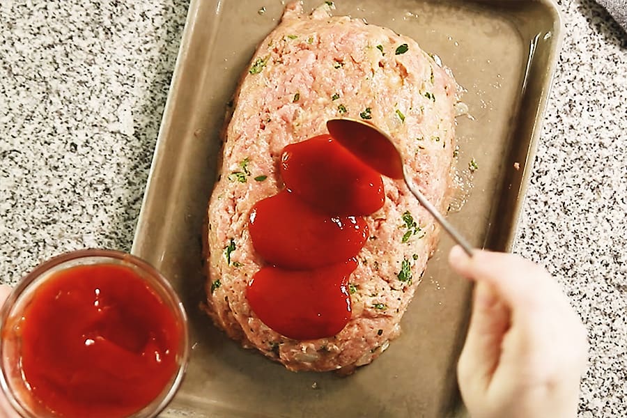 spreading ketchup on meatloaf