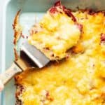 pulling a serving of keto reuben casserole out of a casserole dish