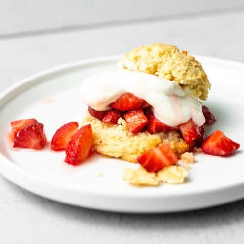 keto shortcake biscuit filled with strawberries and whipped cream on a white plate