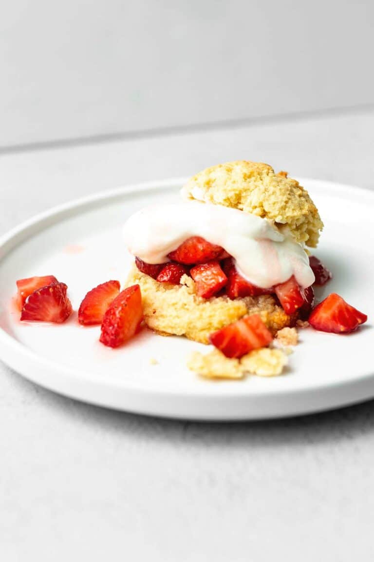 keto shortcake biscuit filled with strawberries and whipped cream on a white plate