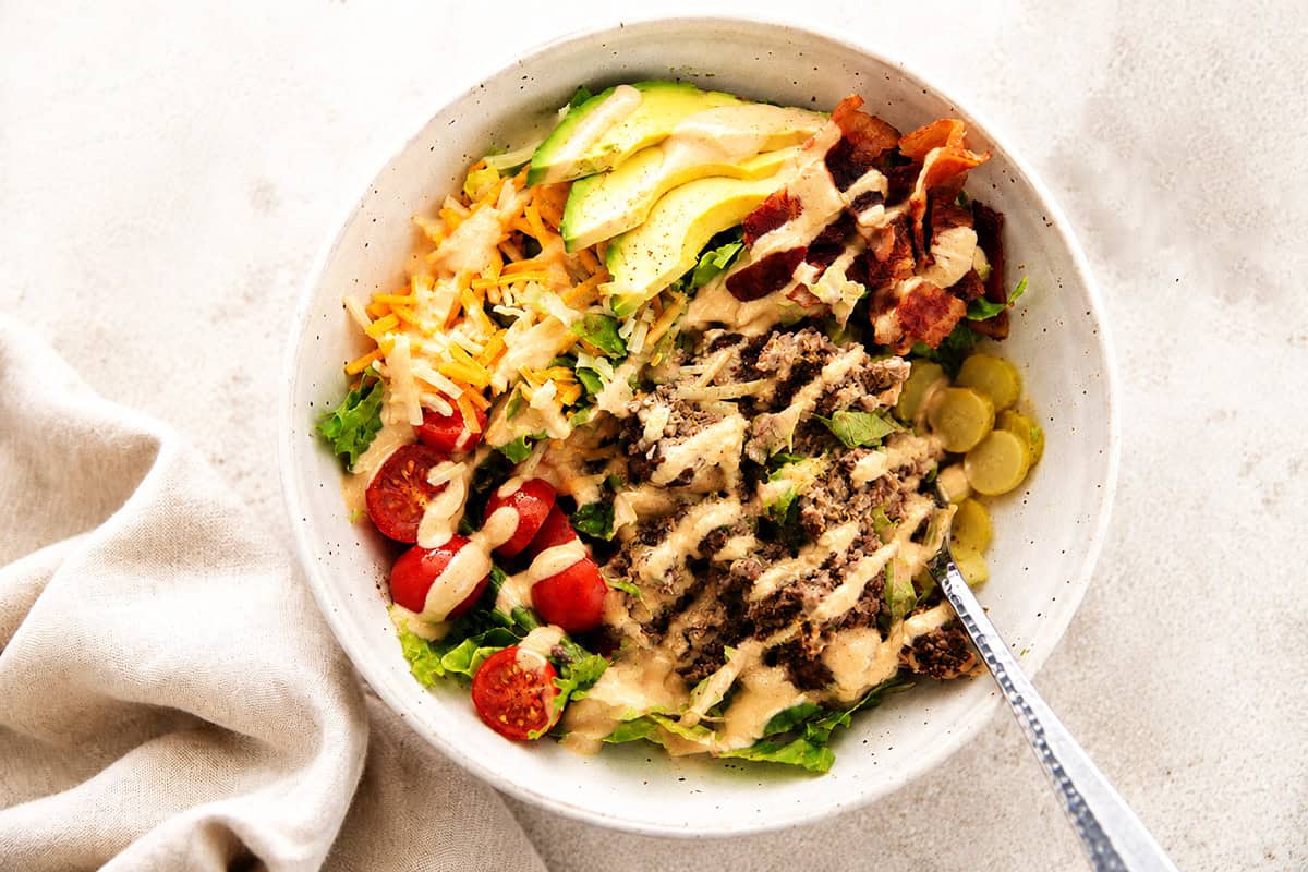 Cheeseburger salad with lettuce, seasoned beef, bacon, avocado, pickles, tomatoes, and creamy Big Mac dressing