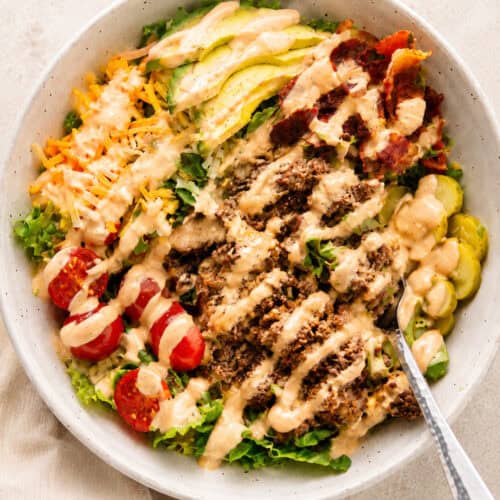 High protein Big Mac salad bowl topped with chopped burgers, crispy bacon, avocado, cheddar cheese, and burger sauce